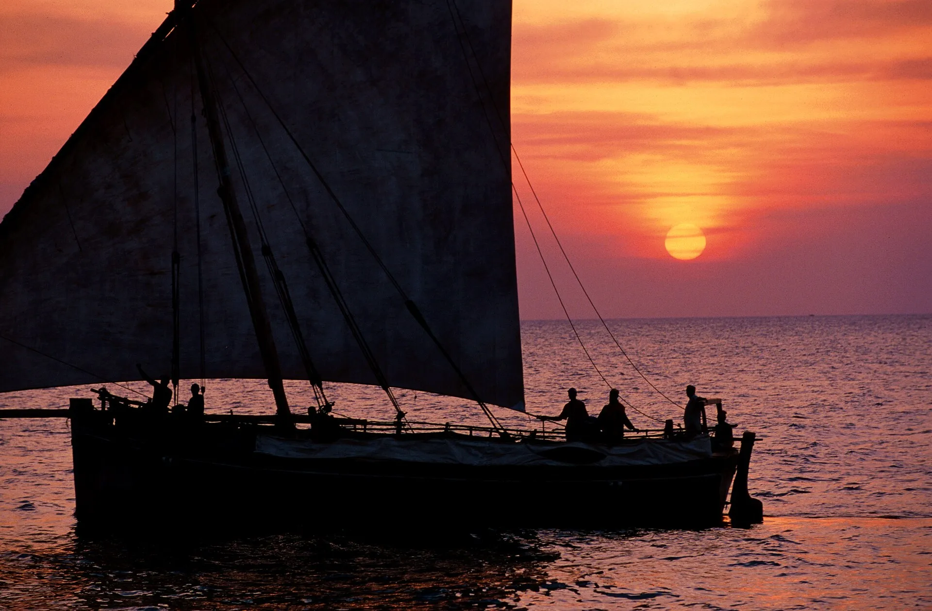 Eine Dhau segelt bei Sonnenuntergang vor Sansibar